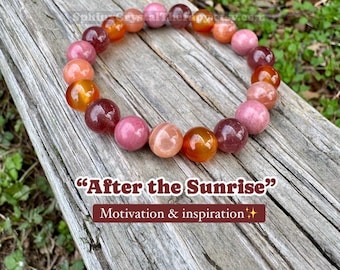 May include: A beaded bracelet featuring smooth, round stones in shades of pink, orange, and deep red. The text "After the Sunrise" and "Motivation & inspiration" is printed below the bracelet, with "SphinxCrystalTherapy.etsy.com" above it.