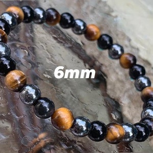 May include: A beaded bracelet featuring alternating 6mm round beads in tiger eye, polished black onyx, and metallic hematite. The stones are arranged in a repeating pattern, showcasing golden brown, deep black, and reflective silver-grey tones.