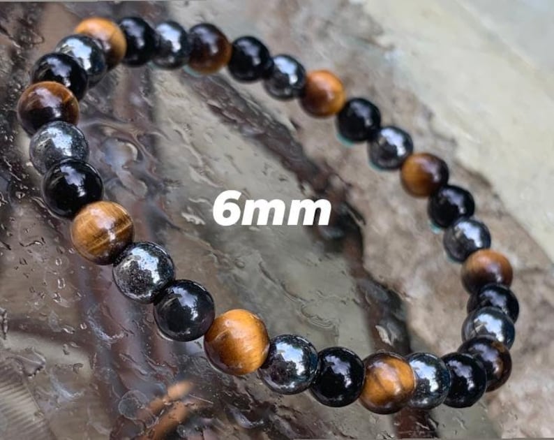 May include: A beaded bracelet featuring alternating 6mm round beads in tiger eye, polished black onyx, and metallic hematite. The stones are arranged in a repeating pattern, showcasing golden brown, deep black, and reflective silver-grey tones.