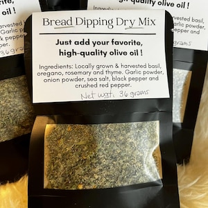 Può includere: Diversi pacchetti neri di mix secco per intingere il pane. Ogni pacchetto ha una finestra trasparente che mostra le erbe e le spezie. L'etichetta recita "Bread Dipping Dry Mix" e "Just add your favorite, high-quality olive oil!"