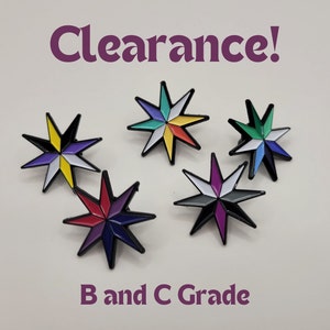 May include: Five multi-coloured eight-pointed star pins with black outlines. The pins are arranged in a semi-circle on a white surface. The text "Clearance!" is at the top of the image and the text "B and C Grade" is at the bottom of the image.
