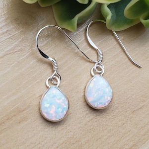 May include: A pair of silver dangle earrings with white opal teardrop-shaped stones.
