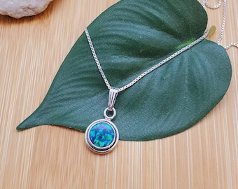 May include: A silver chain necklace with a round pendant featuring a blue and green opal gemstone.