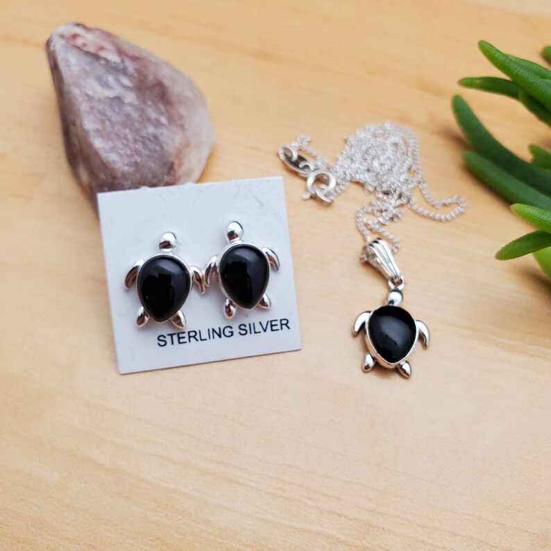 May include: Sterling silver turtle earrings and necklace set with black onyx stones. The earrings are stud style and the necklace has a pendant.