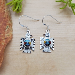 May include: Sterling silver earrings featuring a Native American inspired design of a bird with inlaid turquoise, red, blue, yellow, and black stones.