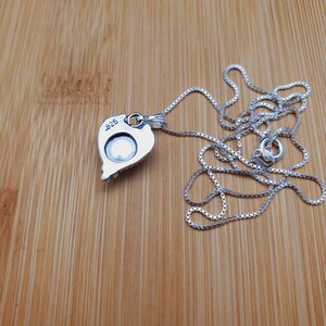 May include: A silver necklace with a heart-shaped pendant. The pendant has a detailed design and the words "925" stamped on the back.