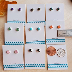 May include: Ten pairs of sterling silver stud earrings with various colored stones. The earrings are displayed on white cards with the words "sterling silver" printed on them. A ruler and two US coins are included for size reference.