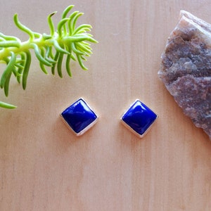 May include: A pair of silver earrings with square blue lapis lazuli stones.