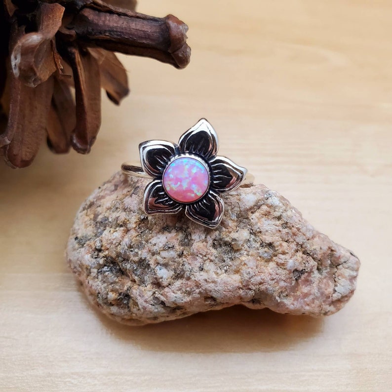 May include: A silver ring with a pink opal flower design.