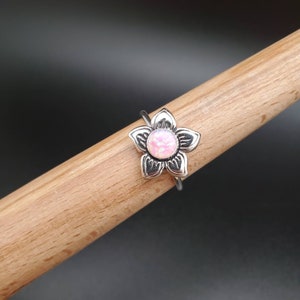 May include: A silver ring with a pink opal flower design.
