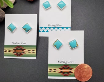 May include: Three pairs of sterling silver earrings with turquoise stones. The earrings are displayed on white cards with a Southwestern design. The cards also have the text "Sterling Silver" printed on them. A penny is included for scale.