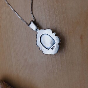 May include: Silver pendant necklace with a detailed design. The back of the pendant is stamped with the number "925".