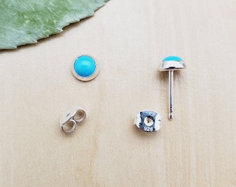 May include: A pair of silver earrings with turquoise stones. The earrings are marked with "925" on the back.