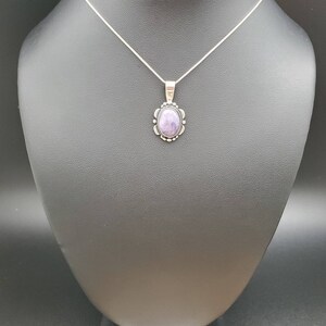 May include: A silver chain necklace with a pendant featuring a purple gemstone set in a silver bezel.