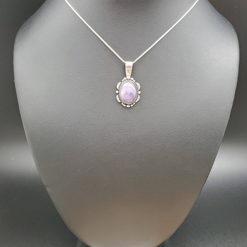 May include: A silver chain necklace with a pendant featuring a purple gemstone set in a silver bezel.