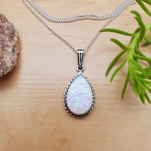 May include: A silver chain necklace with a teardrop-shaped pendant featuring a white opal stone with iridescent shimmer.