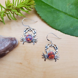 May include: Silver crab earrings with orange and purple opal stones.