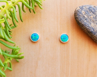 May include: A pair of silver stud earrings with round blue opal stones.