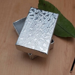 May include: Two silver gift boxes with a textured pattern. The boxes are stacked on top of each other.