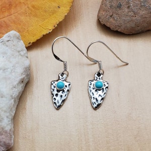 Puede incluir: Un par de pendientes de plata con piedras turquesa en forma de puntas de flecha.