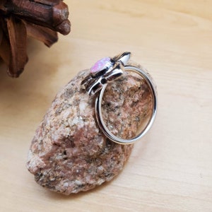 May include: A silver ring with a pink opal stone set in a flower design.