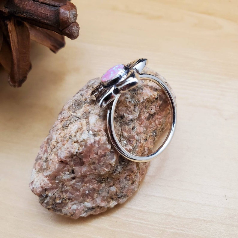 May include: A silver ring with a pink opal stone set in a flower design.