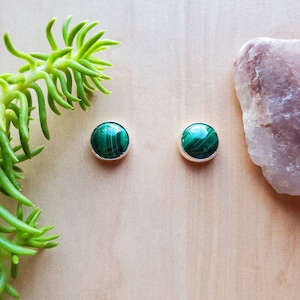May include: A pair of silver stud earrings with round green malachite stones.