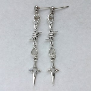 May include: A pair of silver earrings with a barbed wire design and a star-shaped charm.