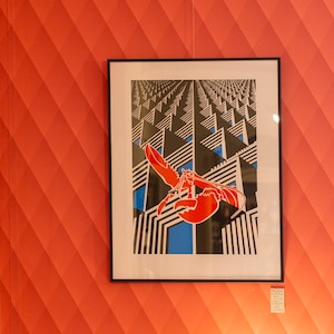 May include: A gallery wall with six framed black and white abstract prints and one framed print of a red lobster in a black and white geometric pattern.