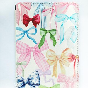 May include: A rectangular case featuring a pattern of watercolor bows in various colors, including red, pink, blue, and green, on a white background. The bows have different patterns and styles, creating a whimsical design.