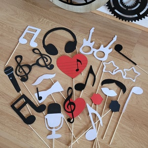 Peut inclure: Un ensemble de 16 accessoires de photomaton en papier noir, blanc et rouge avec des bâtonnets en bois. Les accessoires comprennent des notes de musique, un microphone, un cœur, un nœud papillon, une moustache, des lunettes et des écouteurs.