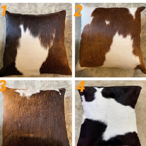 May include: Four square cowhide throw pillows with different color patterns. The pillows are brown and white, brown and white, brown and white, and black and white.