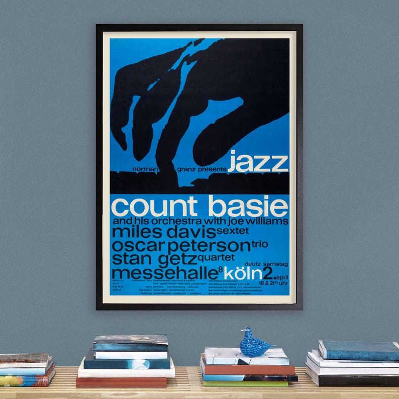 Puede incluir: Un cartel vintage que anuncia un concierto de jazz con Count Basie y su orquesta, Miles Davis, Oscar Peterson y Stan Getz. El cartel es azul y negro con una gran mano tocando el piano. El concierto est&aacute; programado para el 2 de abril en Colonia, Alemania.