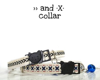 May include: Two cat collars with a white background. The top collar has a black and white chevron pattern and a black cat face buckle. The bottom collar has a red, white, and blue pattern with a black cat face buckle and a blue bell.