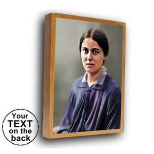 Puede incluir: Un retrato enmarcado de una mujer con cabello oscuro y un vestido azul. La mujer está mirando directamente al espectador. El marco es de madera y tiene un acabado dorado.