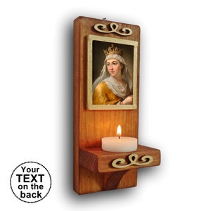 Puede incluir: Portavelas de pared de madera con una pequeña imagen de una mujer con una corona y un velo blanco. El portavelas tiene un pequeño estante para una vela de té y decoración de volutas.