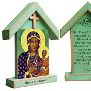 Puede incluir: Un santuario de madera con forma de casa con un exterior pintado de verde. El frente presenta una imagen de la Virgen Negra y el niño con detalles dorados. La parte posterior presenta una oración a la Virgen María en texto negro.