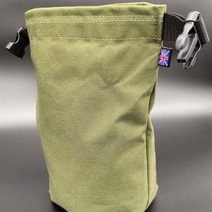 May include: Olive green drawstring bag with black plastic buckles and a black strap. The bag has a small Union Jack tag. The bag is made of a durable, textured fabric.