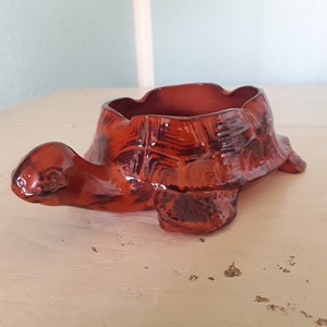 Op de afbeelding: Een bruine keramische asbak in de vorm van een schildpad. De schildpad heeft een gedetailleerde schild en een brede, open mond.