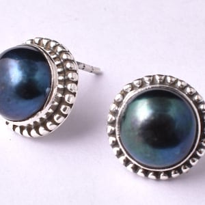 May include: A pair of silver earrings with black pearl accents. The pearls are set in a silver bezel with a beaded edge.