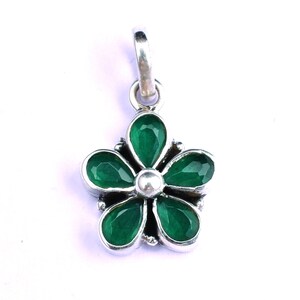 May include: A silver pendant in the shape of a flower with five green gemstones.
