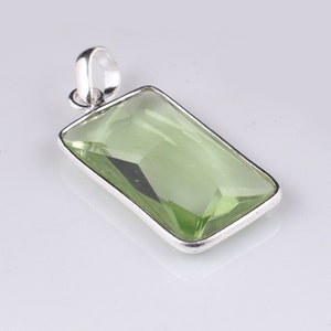 May include: A silver pendant with a light green rectangular gemstone.