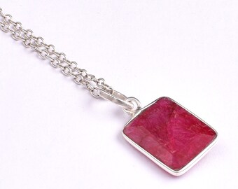 May include: A silver chain necklace with a pendant featuring a square-shaped ruby gemstone.