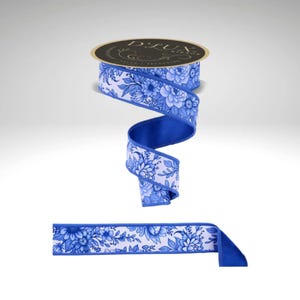 May include: A roll of D.Lux ribbon with a blue and white floral pattern. The ribbon is unrolled to show the blue backing and the floral design. The ribbon is suitable for gift wrapping, crafts, and decorations.