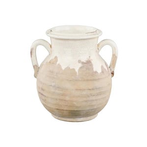 May include: A cream-colored, two-handled vase with a distressed finish. The vase has a wide, rounded body and a narrow neck. The surface has a crackled texture, with areas of brown and beige tones. The handles are curved and attached to the sides of the vase.