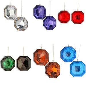 May include: Ten decorative Christmas baubles shaped like faceted gemstones in various colours, including red, blue, green, purple, orange, and clear. Each bauble has a gold string for hanging.
