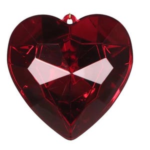 May include: A large, red, heart-shaped, plastic, gem-like ornament. The ornament has a faceted design and a gold string for hanging.