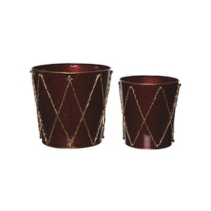 May include: Two cylindrical metal planters in a deep, glossy burgundy finish. Each planter features a decorative gold-toned rope pattern wrapped around the exterior in a diamond lattice design, creating a structured and uniform appearance.