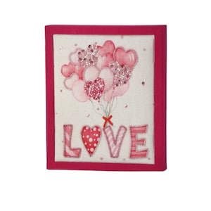 May include: A framed canvas with a pink and white heart-shaped balloon design and the word "LOVE" in pink and white letters.