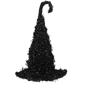 May include: A black witch hat constructed from a textured, twig-like material with a pointed, curved top. The surface of the hat is covered in small, scattered white specks that provide a subtle contrast against the dark, fibrous structure.